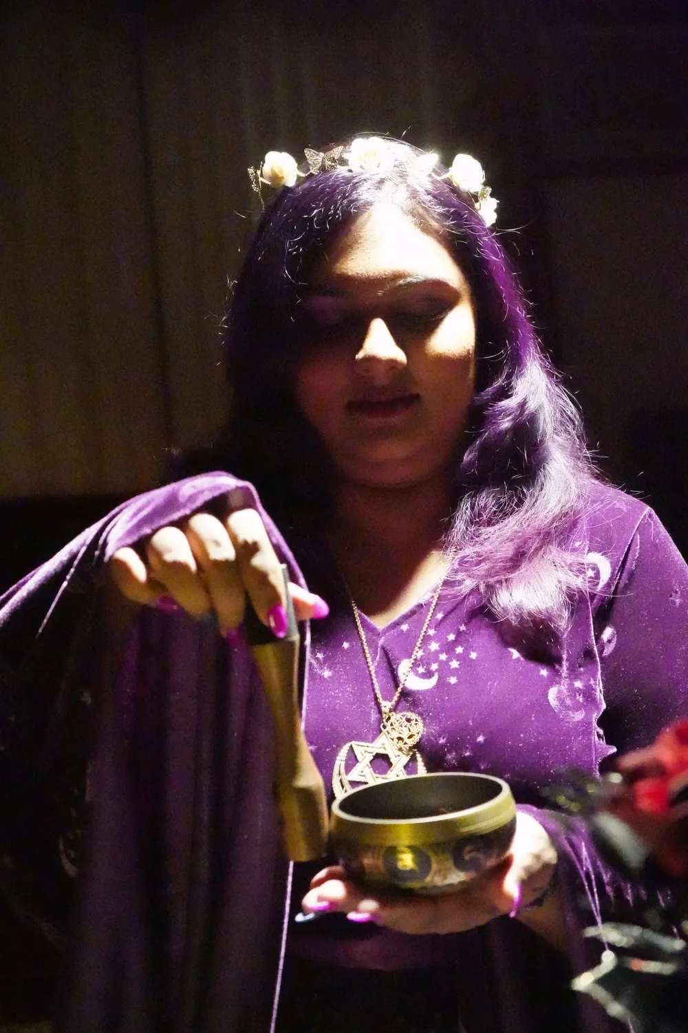 Ashley Ali holding a brass singing bowl under a spotlight